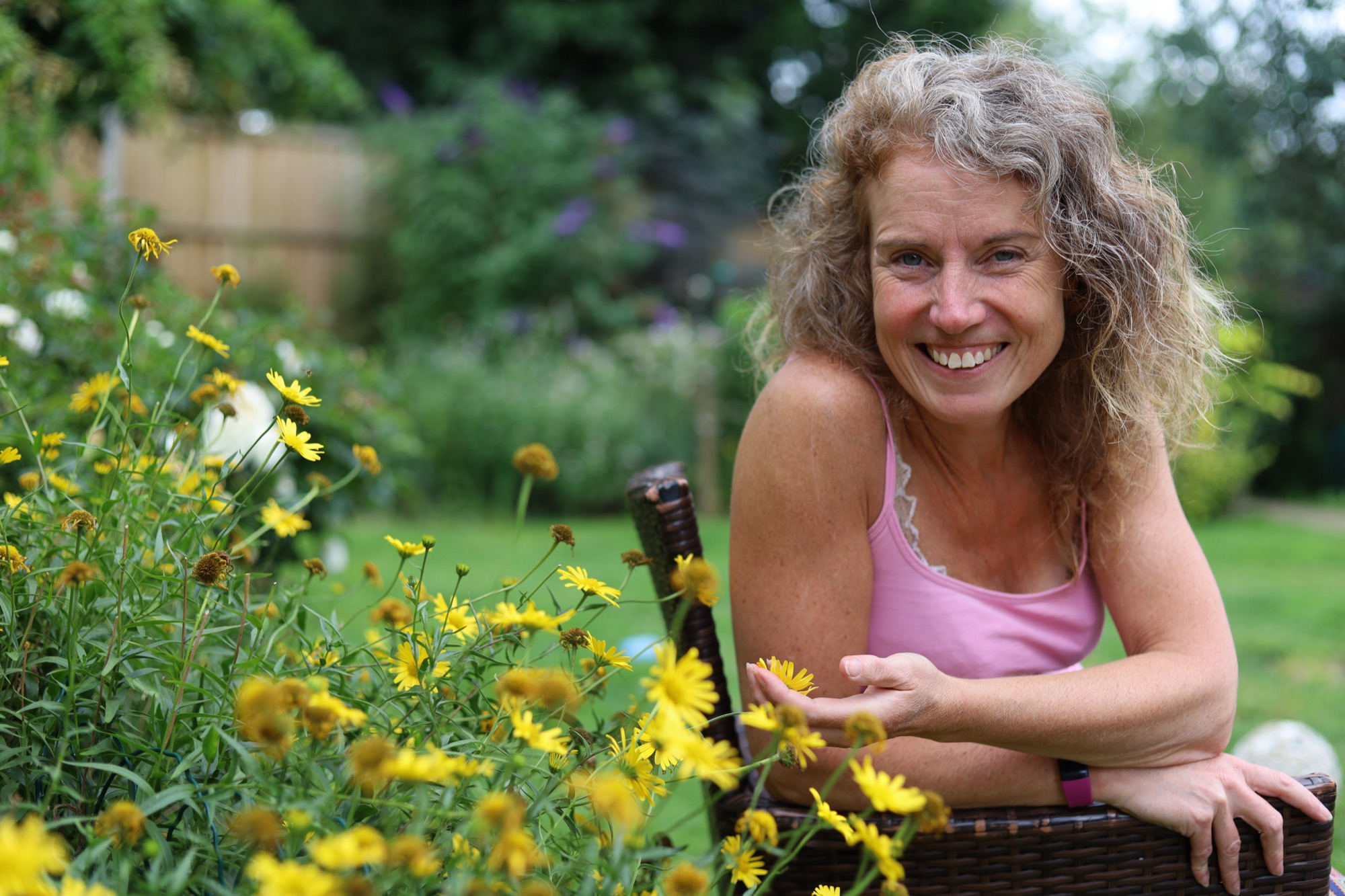 Gina smiling among yellow flowers
